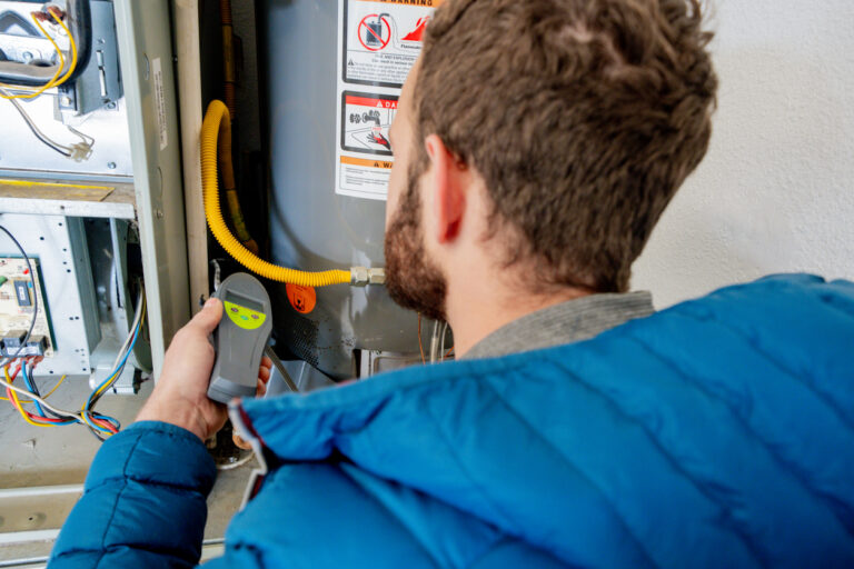 HVAC questions: Over-the-shoulder POV of HVAC technician inspecting a unit of an older home.